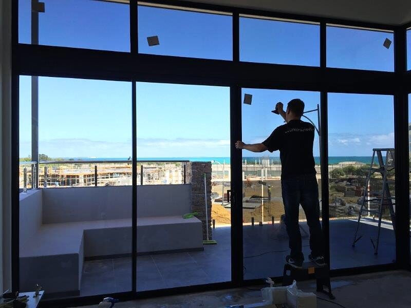 Installer applying commercial window film to a Miami building